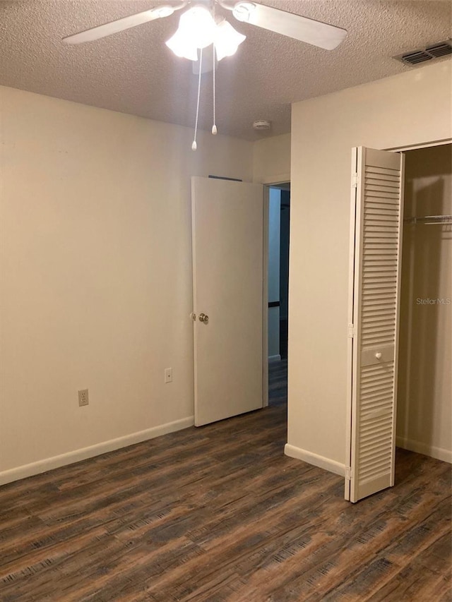 unfurnished bedroom featuring a closet, dark hardwood / wood-style floors, a textured ceiling, and ceiling fan