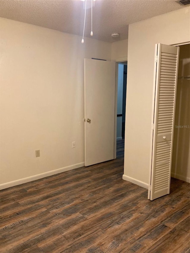 unfurnished bedroom with dark hardwood / wood-style flooring, a closet, and a textured ceiling