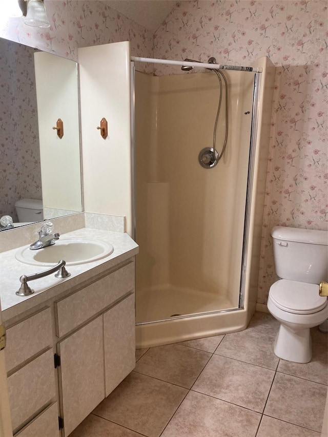 bathroom featuring tile patterned flooring, vanity, toilet, and walk in shower