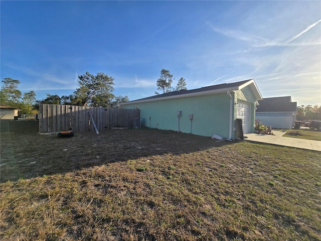 view of home's exterior featuring cooling unit, a yard, and a garage