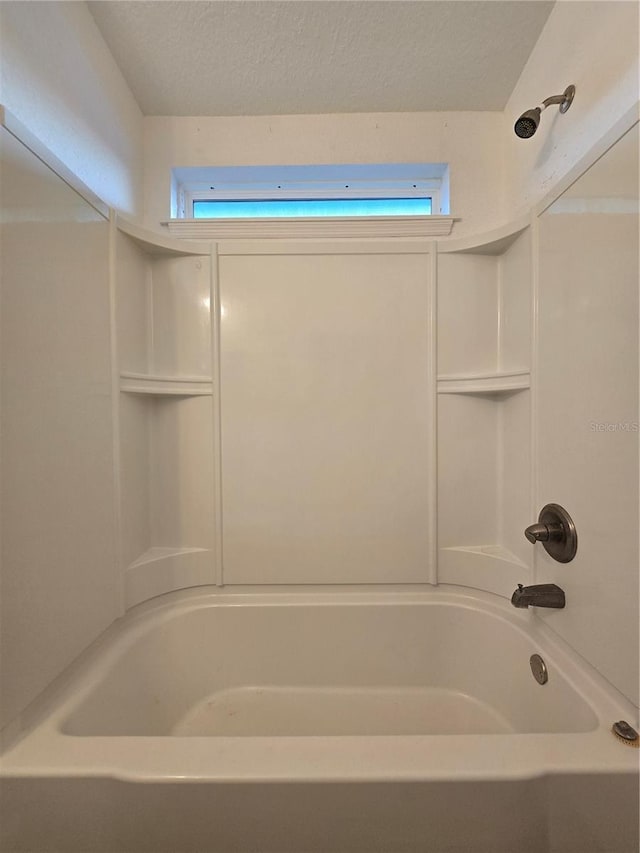 bathroom with bathing tub / shower combination, a textured ceiling, and a wealth of natural light