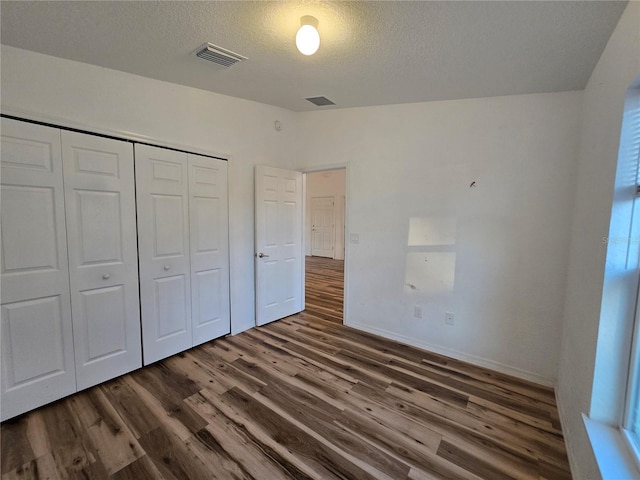 unfurnished bedroom featuring dark hardwood / wood-style floors, a closet, and a textured ceiling