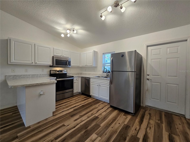 kitchen with appliances with stainless steel finishes, lofted ceiling, sink, white cabinets, and kitchen peninsula