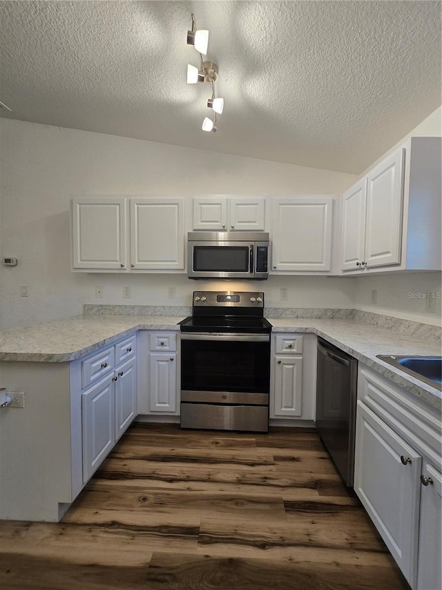 kitchen with lofted ceiling, white cabinetry, a textured ceiling, dark hardwood / wood-style floors, and stainless steel appliances