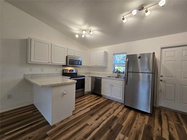 kitchen with white cabinetry, vaulted ceiling, dark hardwood / wood-style flooring, kitchen peninsula, and stainless steel appliances