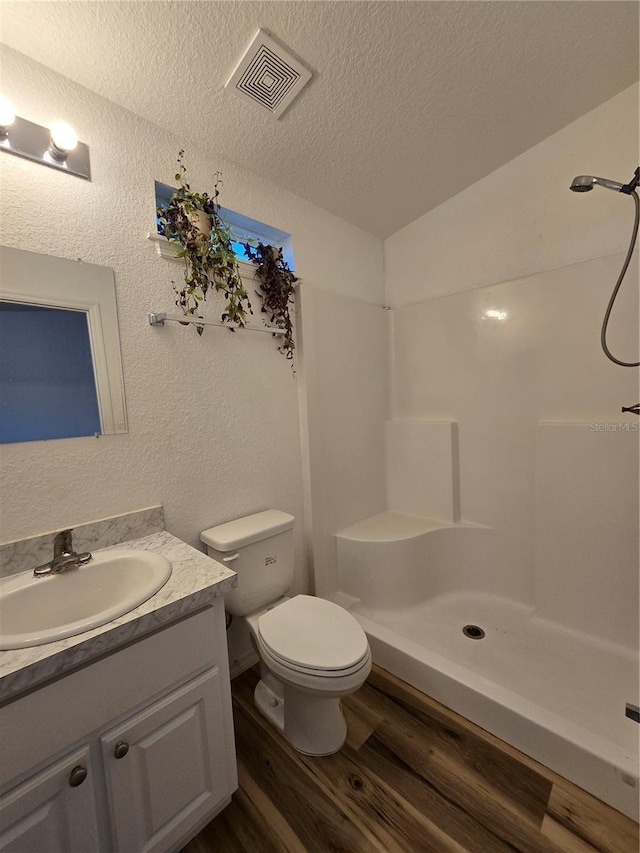 bathroom with a shower, hardwood / wood-style flooring, vanity, toilet, and a textured ceiling