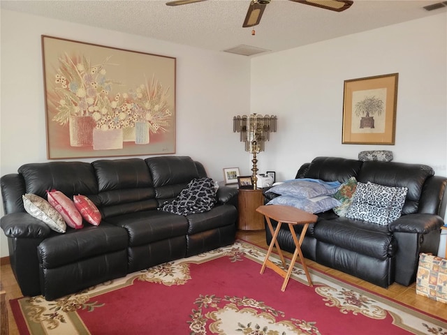 living room featuring ceiling fan and a textured ceiling