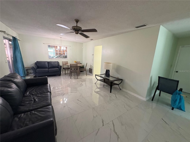 living room with ceiling fan and a textured ceiling