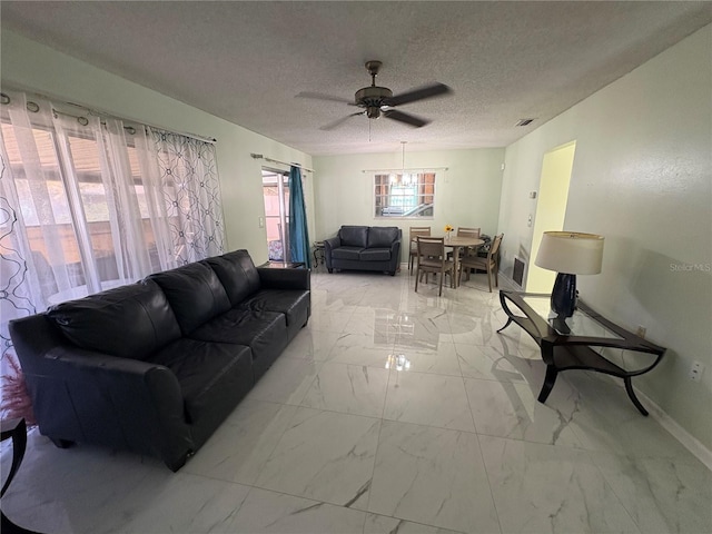 living room featuring ceiling fan and a textured ceiling