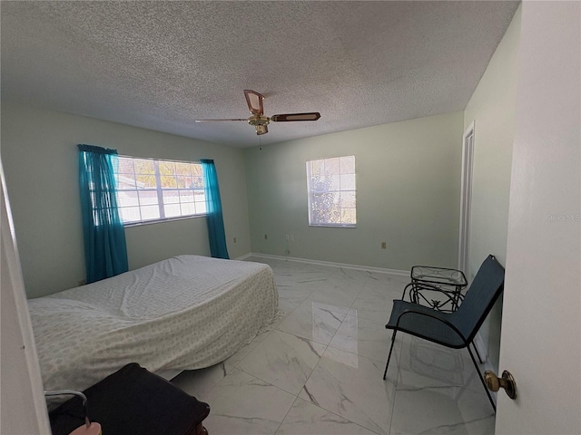 bedroom with ceiling fan and a textured ceiling