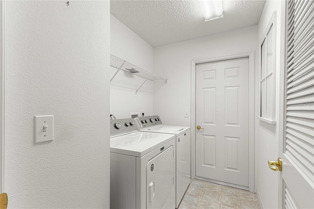 washroom featuring washing machine and dryer and a textured ceiling