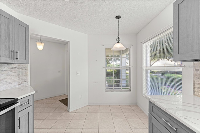 unfurnished dining area with gray cabinets, light tile patterned flooring, and pendant lighting