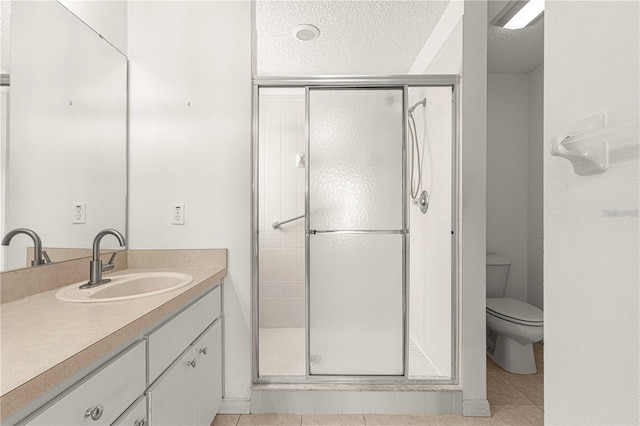 bathroom featuring vanity, a shower with shower door, a textured ceiling, and toilet