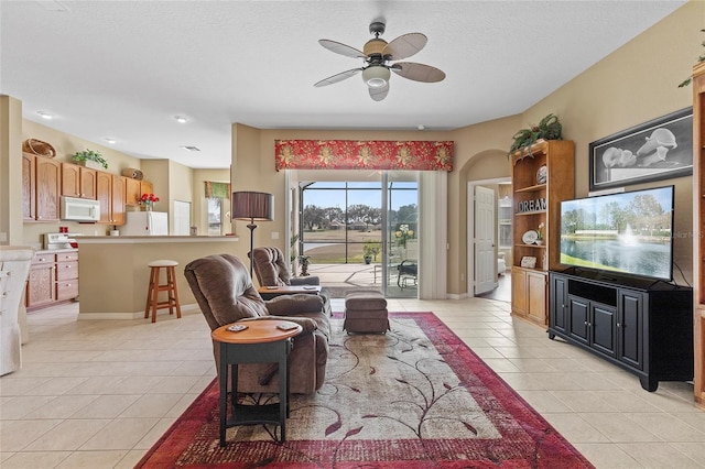 tiled living room with a textured ceiling and ceiling fan