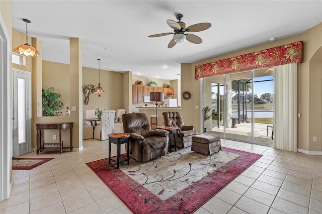 living room featuring ceiling fan with notable chandelier, a textured ceiling, and light tile patterned floors