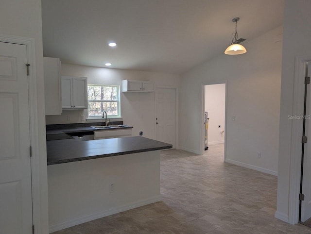 kitchen featuring white cabinetry, hanging light fixtures, vaulted ceiling, and sink