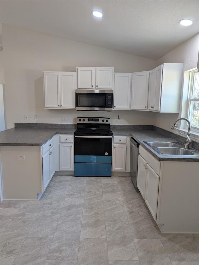 kitchen with lofted ceiling, sink, kitchen peninsula, stainless steel appliances, and white cabinets