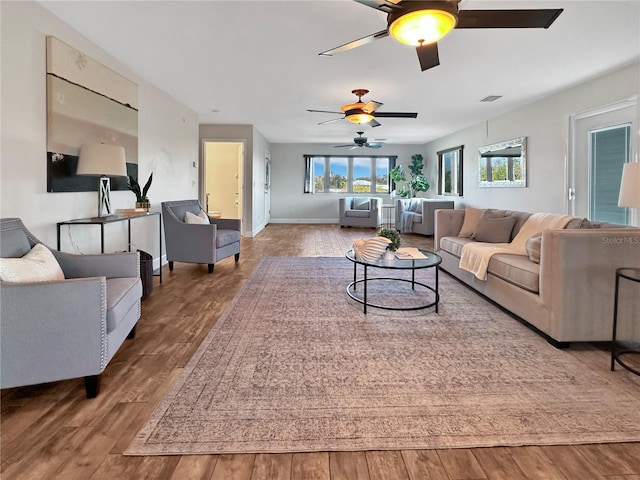 living room with wood finished floors, visible vents, and baseboards