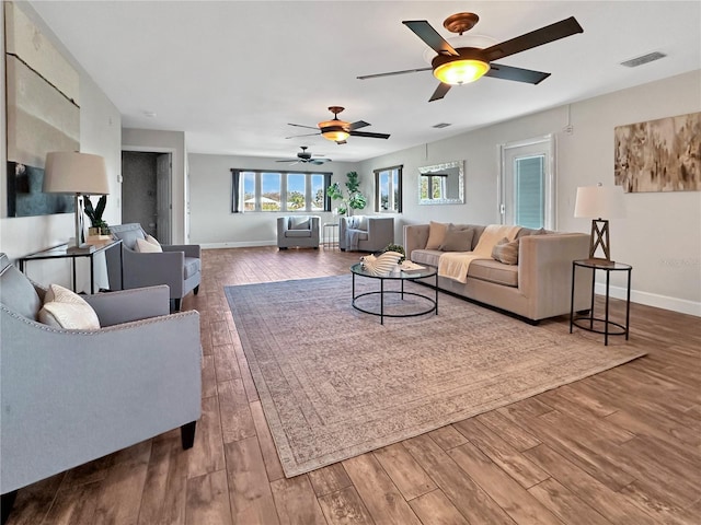 living area featuring visible vents, baseboards, and wood finished floors