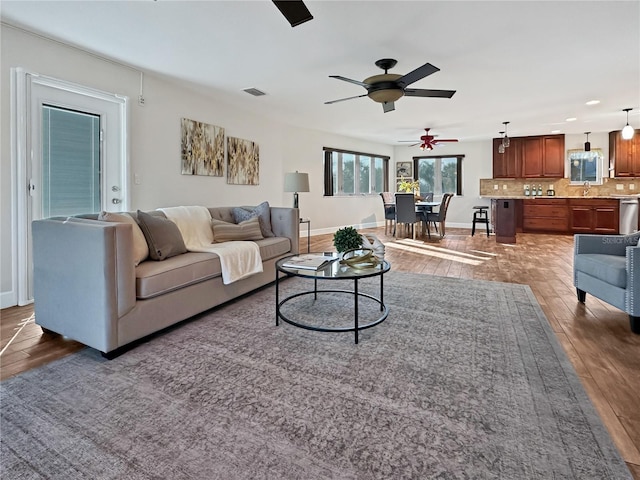 living room with visible vents, ceiling fan, baseboards, and wood finished floors