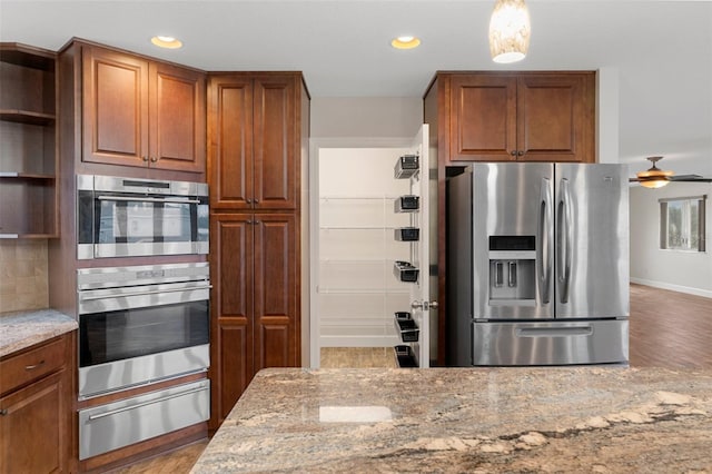 kitchen with appliances with stainless steel finishes, a warming drawer, open shelves, and light stone countertops