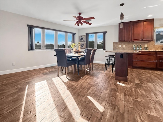 dining area with dark wood-style floors, ceiling fan, and baseboards