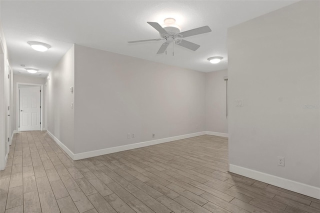 spare room featuring ceiling fan, light wood-style flooring, and baseboards