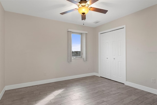 unfurnished bedroom with a closet, visible vents, ceiling fan, light wood-type flooring, and baseboards