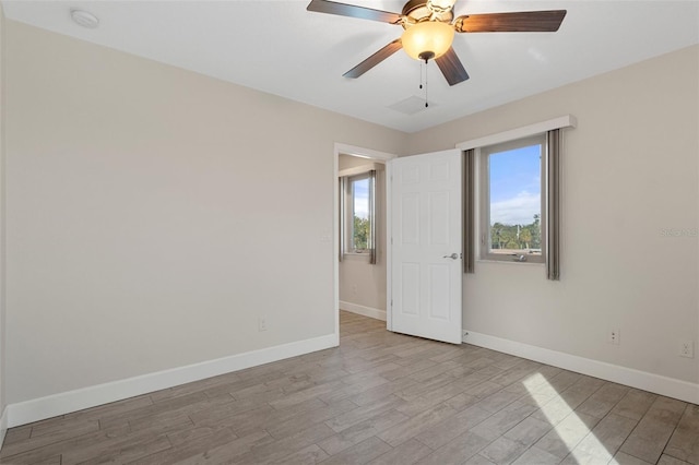 spare room featuring ceiling fan, light wood-type flooring, and baseboards