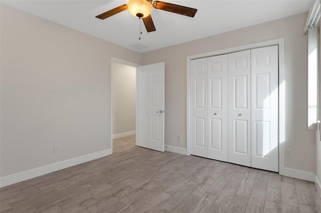 unfurnished bedroom featuring a ceiling fan, a closet, light wood-style flooring, and baseboards