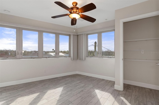 interior space featuring ceiling fan, light wood finished floors, and baseboards