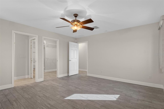 unfurnished bedroom with light wood-style floors, visible vents, a spacious closet, and baseboards