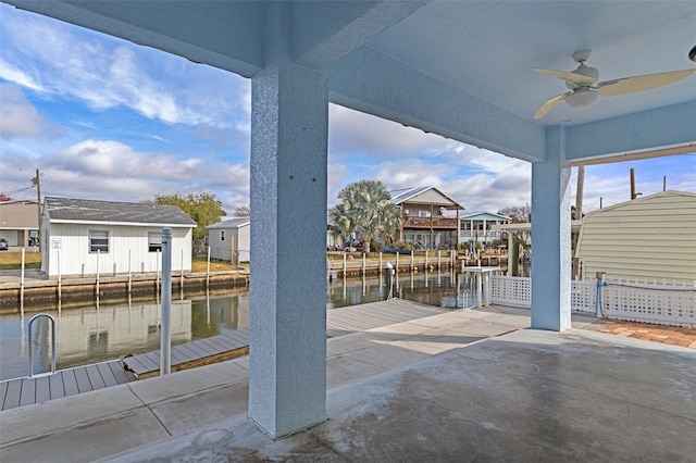 view of patio / terrace with a water view, fence, a ceiling fan, a residential view, and a dock