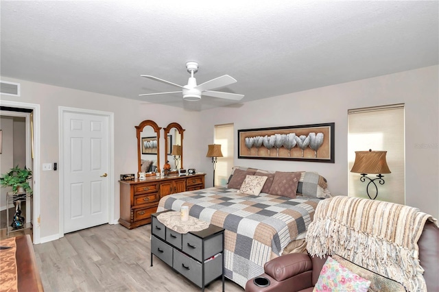 bedroom with a textured ceiling, ceiling fan, and light wood-type flooring