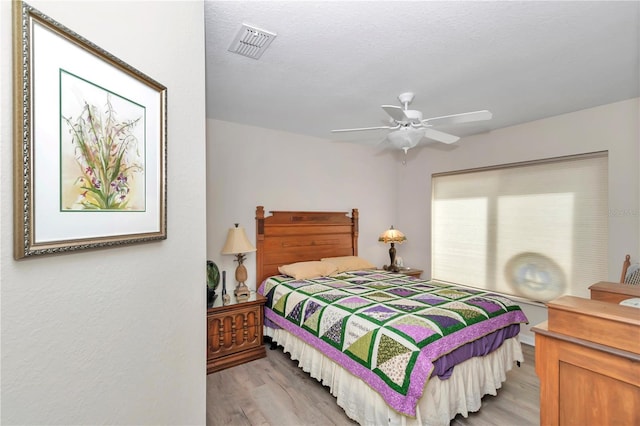 bedroom with ceiling fan, a textured ceiling, and light hardwood / wood-style floors