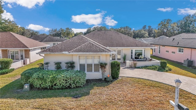 single story home with cooling unit and a front lawn