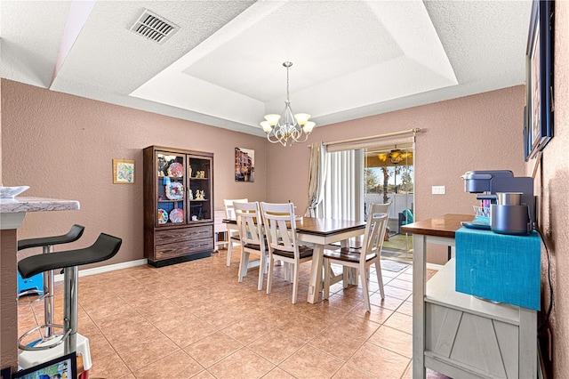 tiled dining area with a textured ceiling, an inviting chandelier, and a tray ceiling