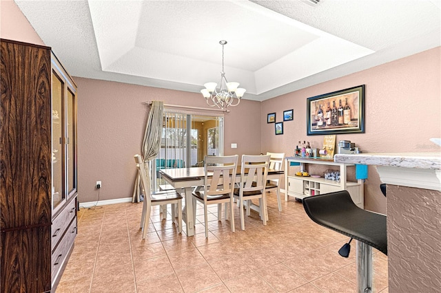 dining area with a tray ceiling, a chandelier, a textured ceiling, and light tile patterned floors