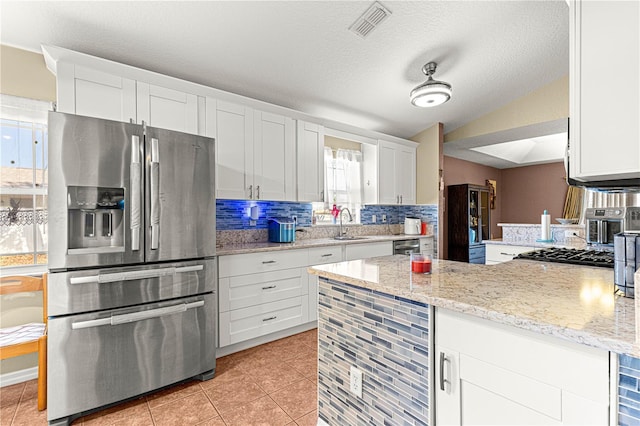 kitchen with light tile patterned flooring, white cabinetry, backsplash, stainless steel refrigerator with ice dispenser, and light stone countertops