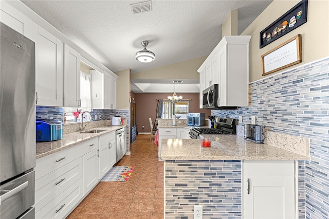 kitchen with sink, white cabinetry, appliances with stainless steel finishes, kitchen peninsula, and pendant lighting