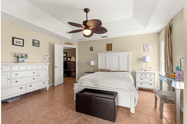 bedroom featuring tile patterned flooring, ceiling fan, a tray ceiling, and a textured ceiling