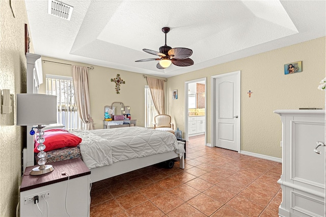 tiled bedroom with ceiling fan, a raised ceiling, a textured ceiling, and ensuite bathroom