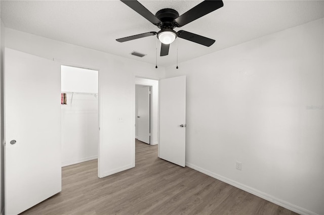 unfurnished bedroom featuring ceiling fan, a closet, and light hardwood / wood-style flooring