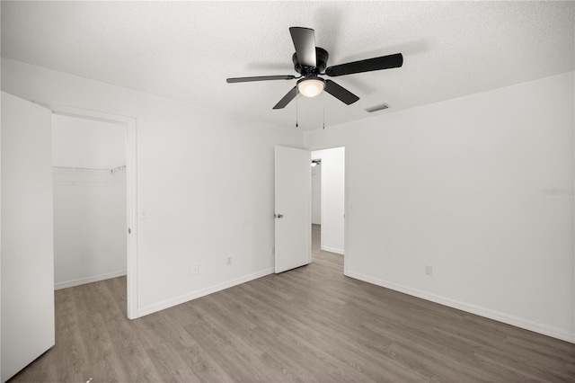 empty room featuring ceiling fan, light hardwood / wood-style flooring, and a textured ceiling