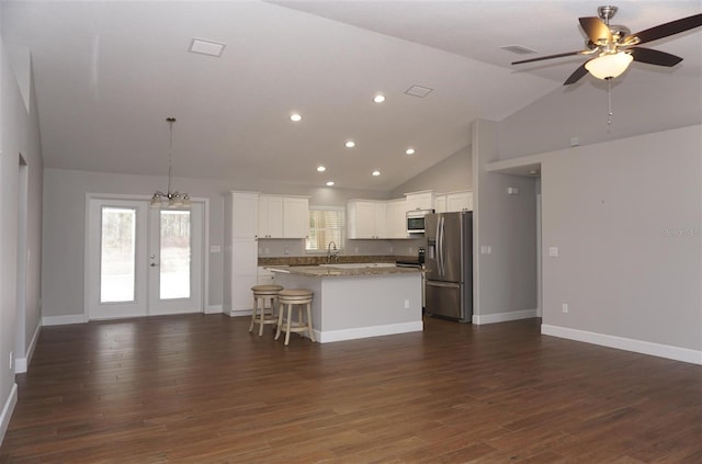 kitchen with stainless steel appliances, a center island, light stone countertops, white cabinets, and french doors