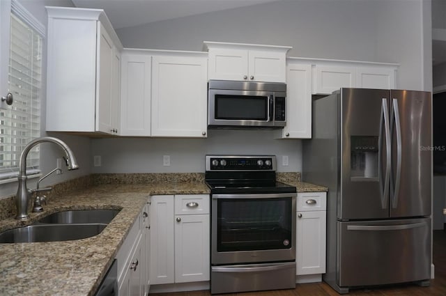 kitchen featuring stainless steel appliances, light stone countertops, sink, and white cabinets