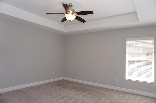 carpeted spare room featuring a raised ceiling and ceiling fan