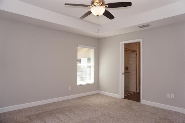 empty room featuring ceiling fan, a tray ceiling, and carpet flooring