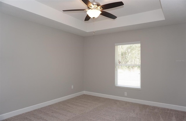 carpeted empty room featuring a raised ceiling and ceiling fan