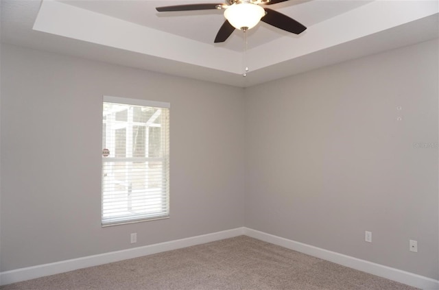 empty room featuring carpet, ceiling fan, and a tray ceiling